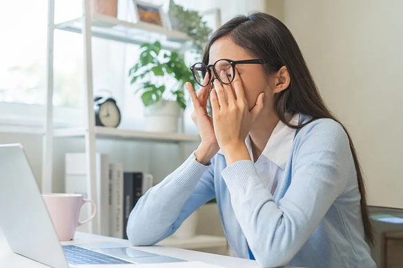 Vehicle owner rubbing her eyes at a laptop while working through registration paperwork